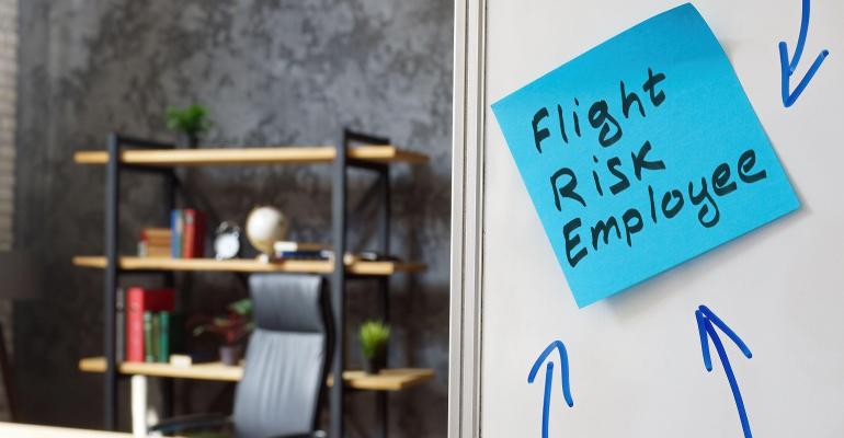 blue sticky note on office door with the words "flight risk employee"