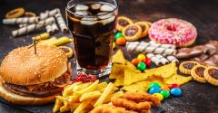 Burger, sweets, chips, chocolate, donuts, soda on a dark background