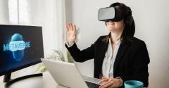 businesswoman wearing goggles facing computer screen with word "metaverse" on it